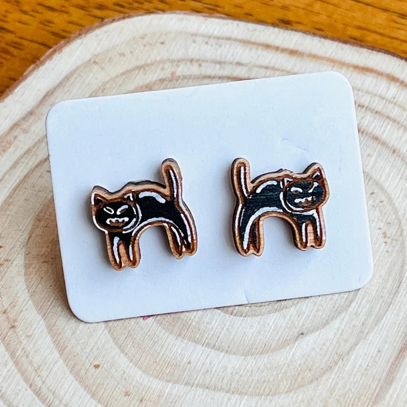 A pair of wooden cat-shaped earrings are displayed on a white card.