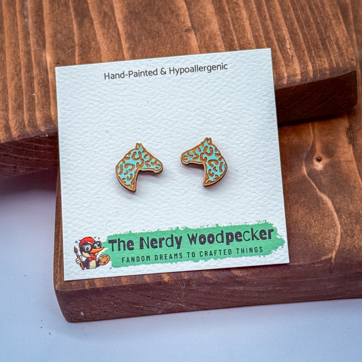 a pair of earrings with a wooden packaging, featuring a cartoon character and text related to the earrings.