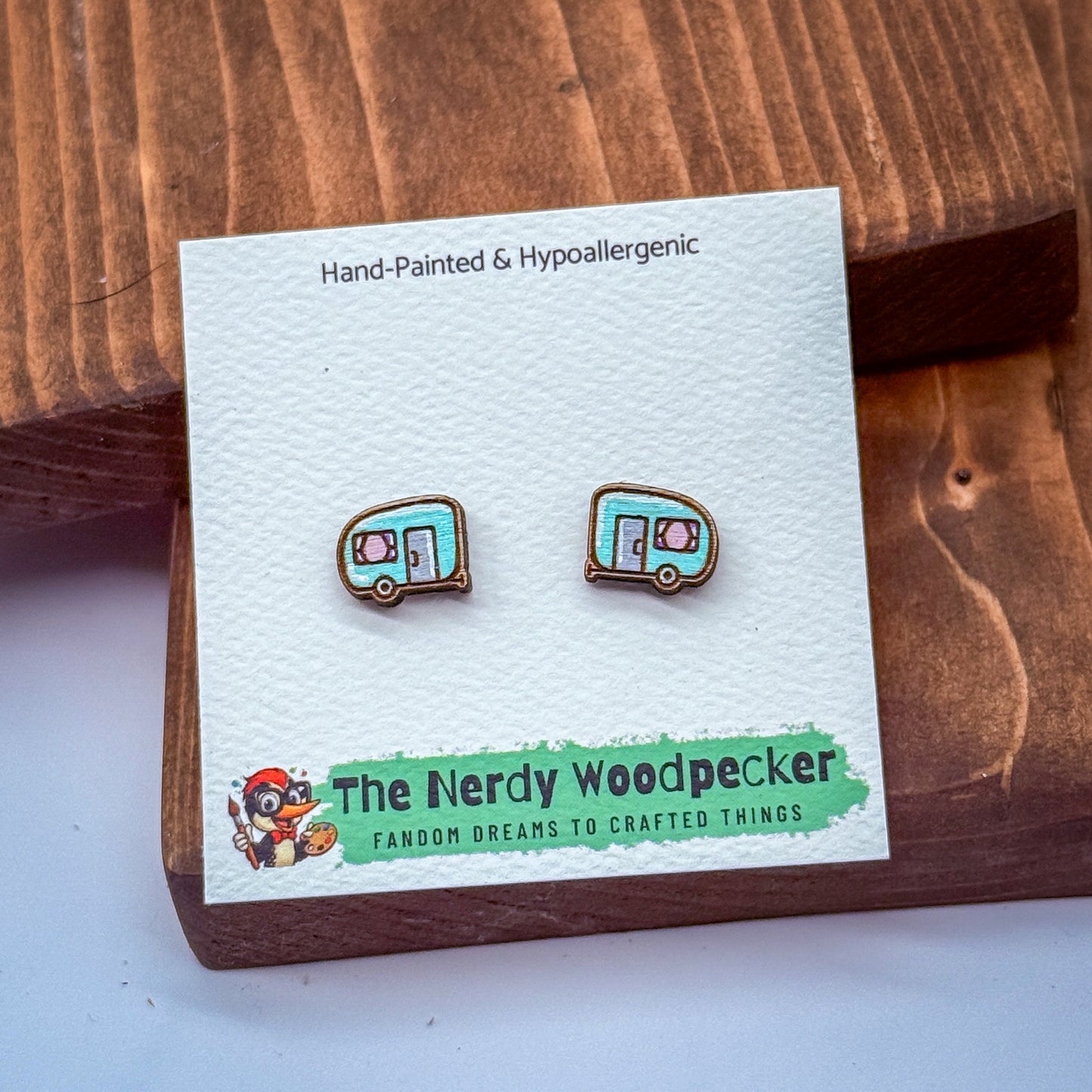 a pair of earrings on a white card with text and a cartoon character illustration.