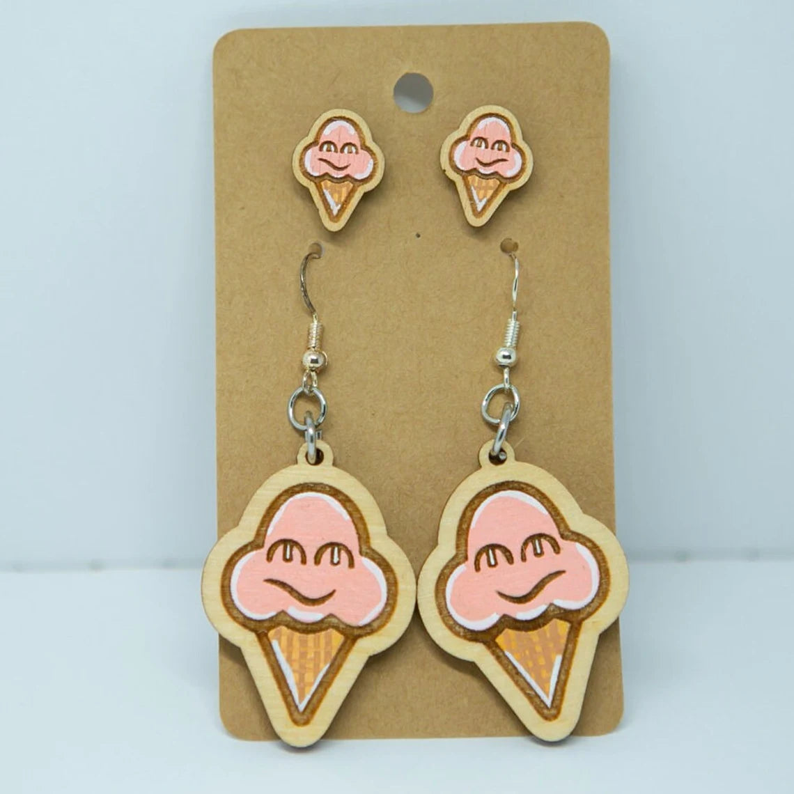 A pair of earrings with wooden ice cream cone designs, featuring two larger earrings and a smaller earring.