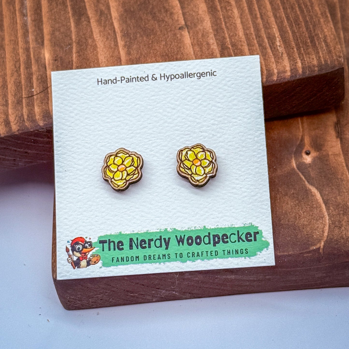 a pair of earrings displayed on a wooden surface, with a card or packaging that provides information about the earrings.