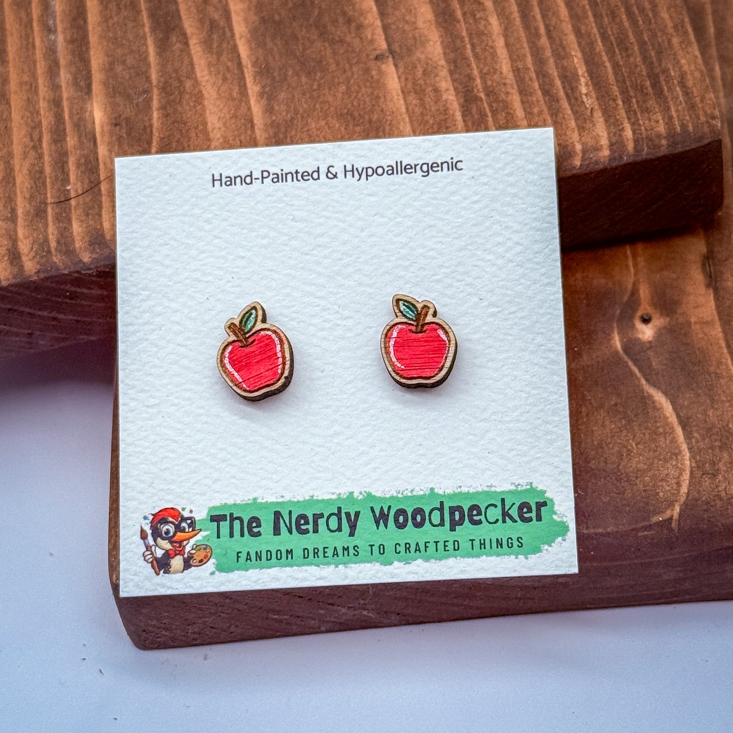 a pair of red earrings with a cartoon character on the packaging, placed on a wooden surface.