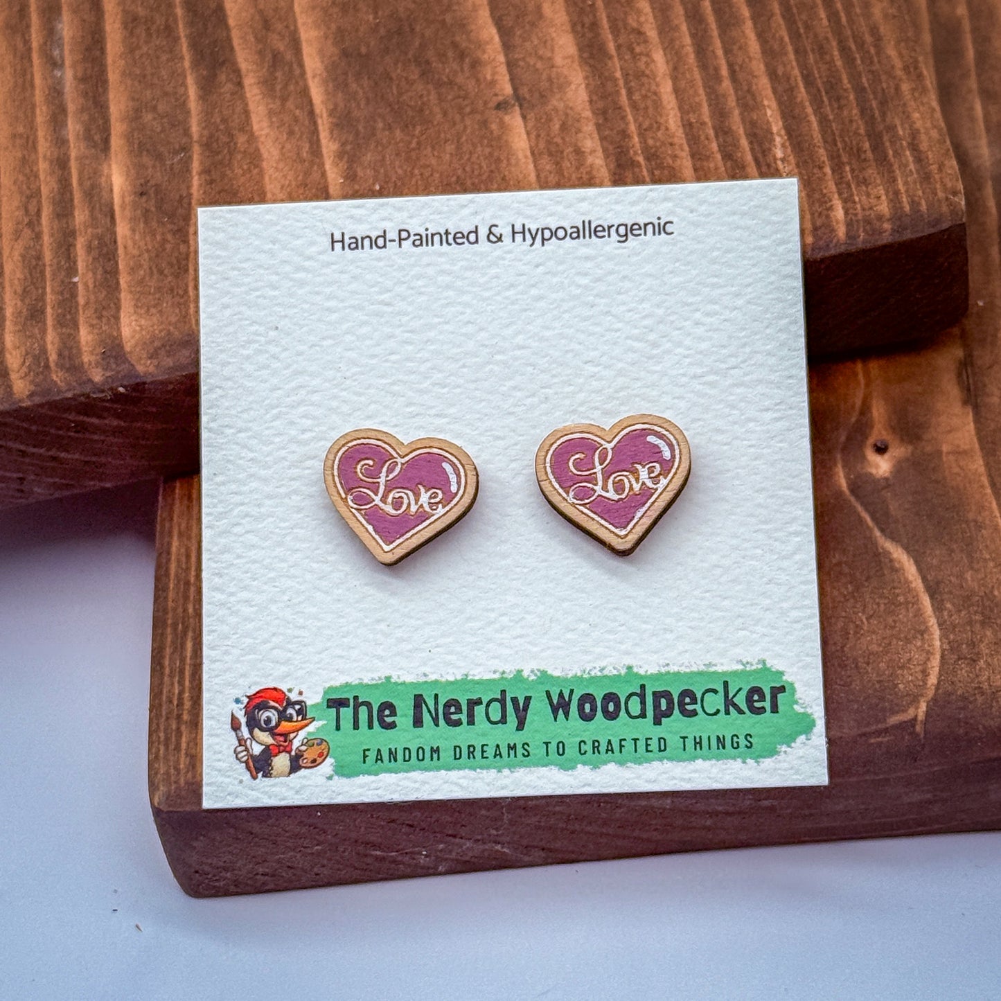 a pair of earrings with the word "Love" engraved on them, placed on a wooden surface.