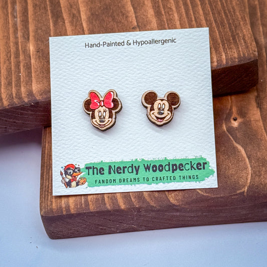 a pair of earrings shaped like Minnie Mouse and Woodpecker, with a wooden background.