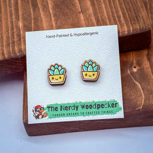 a pair of hand-painted and hypoallergenic earrings with a cute plant design, displayed on a wooden surface.