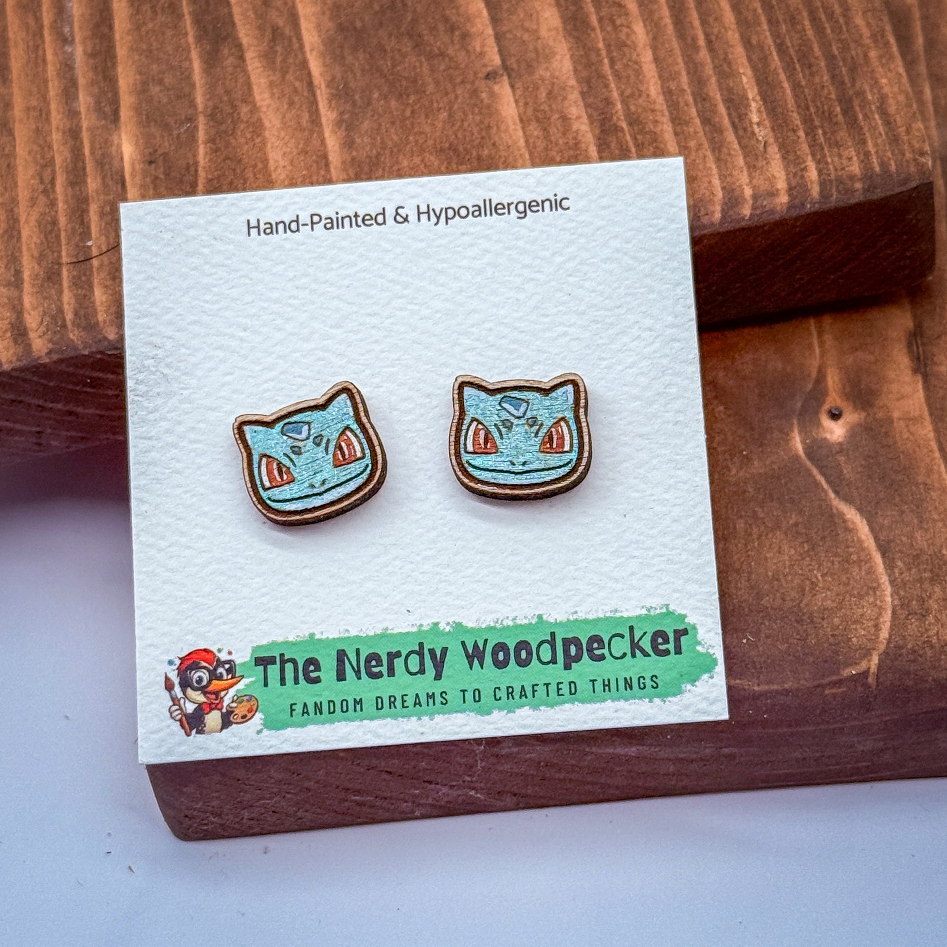 a pair of earrings with a blue and orange design, placed on a white card with text and a cartoon character.