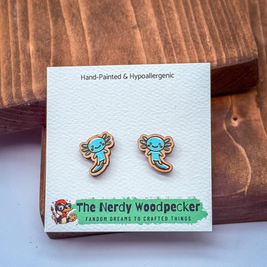 a pair of hand-painted and hypoallergenic earrings in the shape of a woodpecker, displayed on a wooden surface.