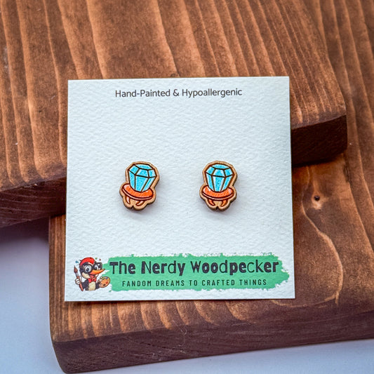 a pair of hand-painted hypoallergenic earrings in the shape of a woodpecker, displayed on a wooden surface.