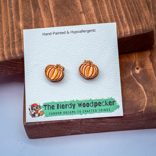 a pair of hand-painted and hypoallergenic earrings with a wooden background, accompanied by a green banner that reads "The Nerdy Woodpecker FANDOM DREAMS TO CRAFTED THINGS".