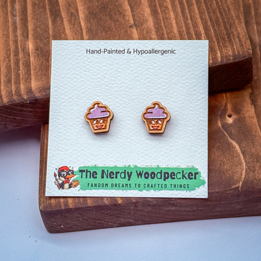 A pair of hand-painted and hypoallergenic earrings in the shape of cupcakes, displayed on a wooden surface.