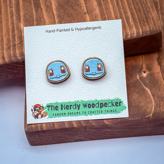 a pair of hand-painted and hypoallergenic earrings with a blue and orange design, placed on a wooden surface.