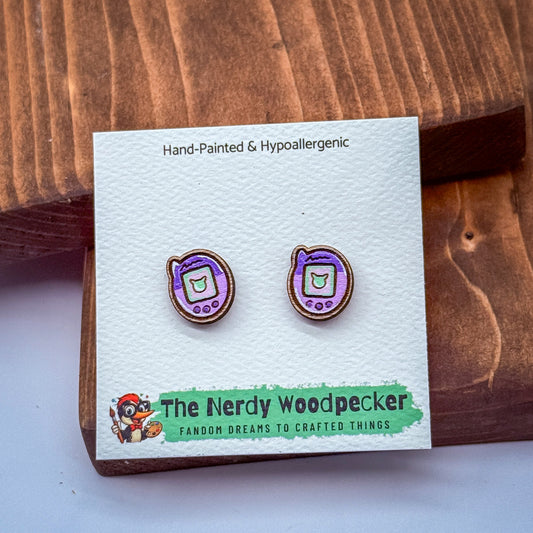a pair of hand-painted hypoallergenic earrings with a purple and purple-themed design, displayed on a white card with text and a cartoon character.