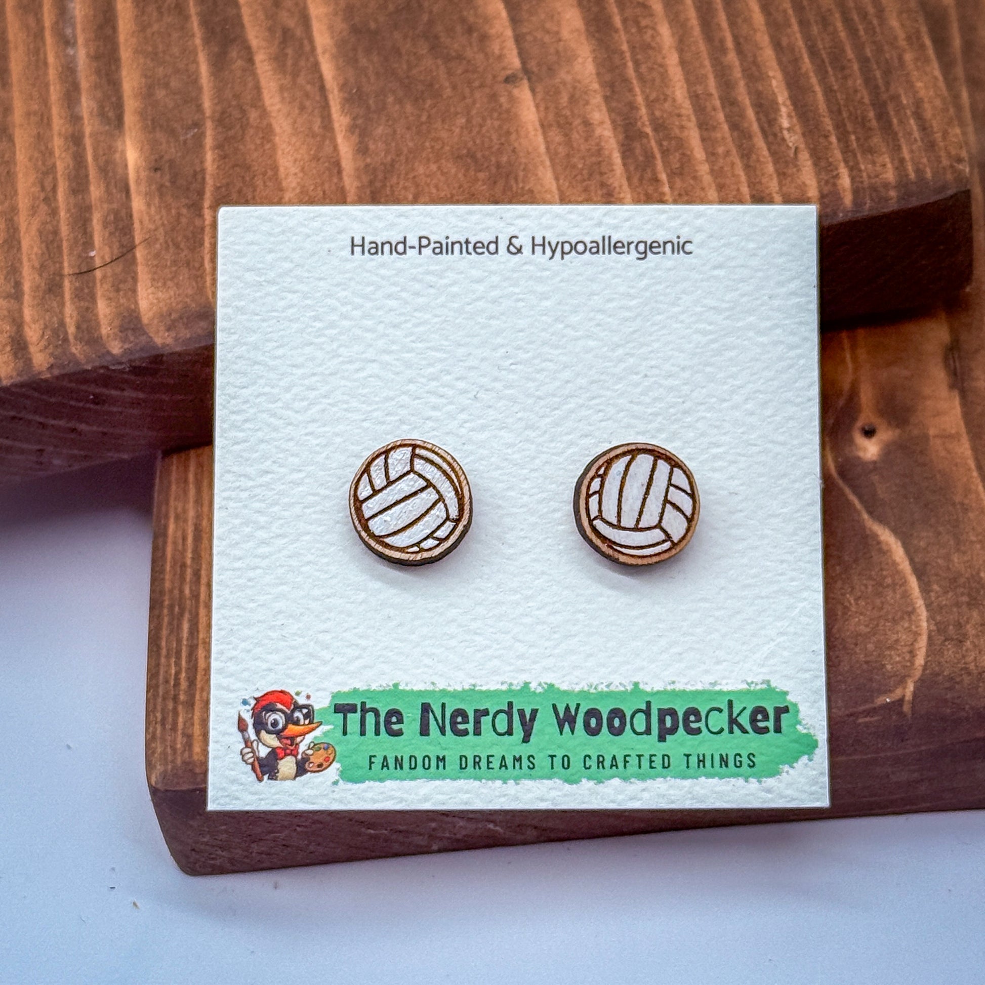 a pair of wooden earrings on a white card, with a cartoon character and text related to the earrings.