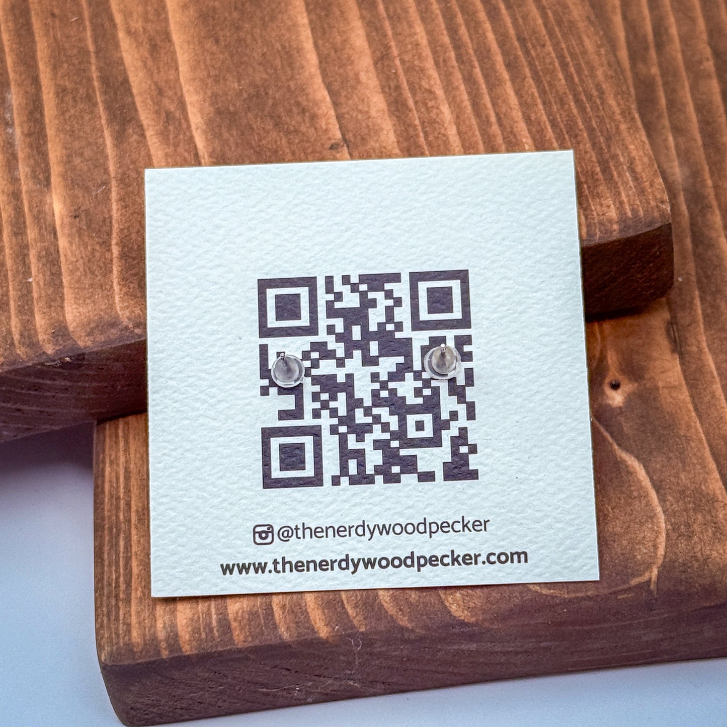 a white card with a QR code and text, placed on a wooden surface.