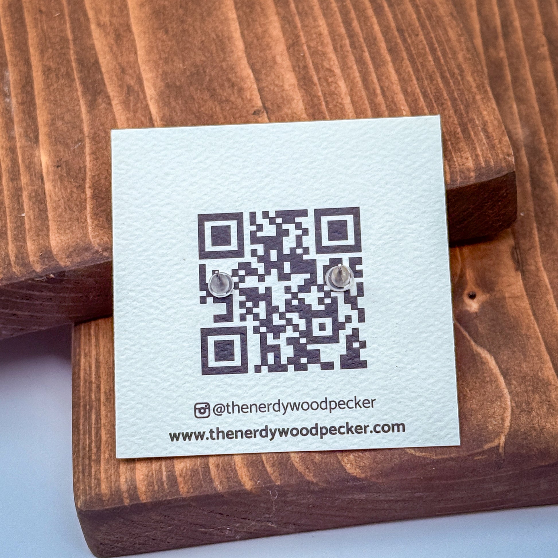a white card with a QR code and text, placed on a wooden surface.
