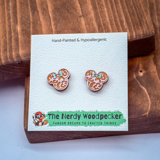 A pair of hand-painted and hypoallergenic earrings in the shape of Mickey Mouse ears, displayed on a wooden surface.