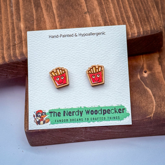 a pair of earrings with a cartoon character design, placed on a white card with text and a logo.