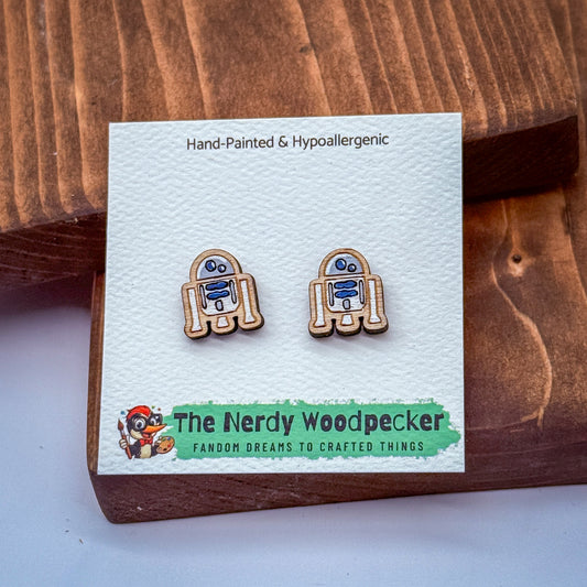 a pair of hand-painted wooden earrings with a hypoallergenic design, displayed on a white card with text and a cartoon character.