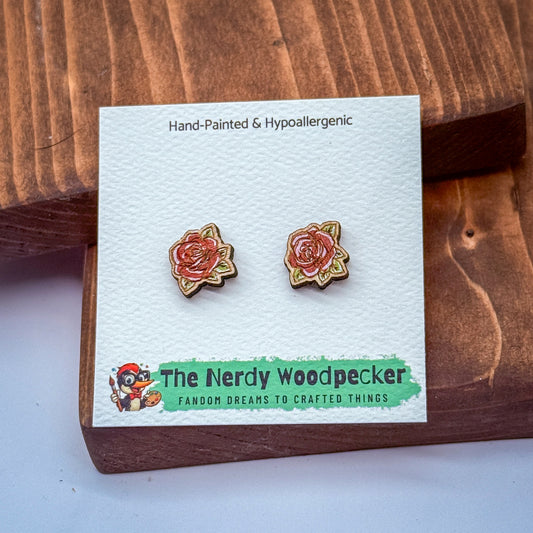 a pair of hand-painted and hypoallergenic earrings displayed on a wooden surface. The earrings are part of a product from "The Nerdy Woodpecker", a fan of crafting and creating things.