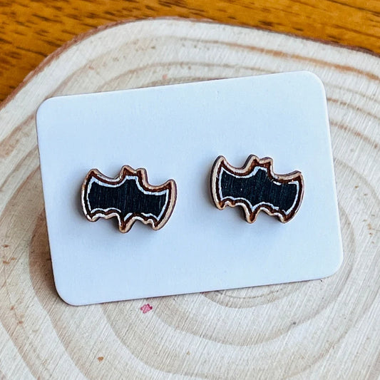 A pair of wooden bat-shaped earrings are displayed on a white card.