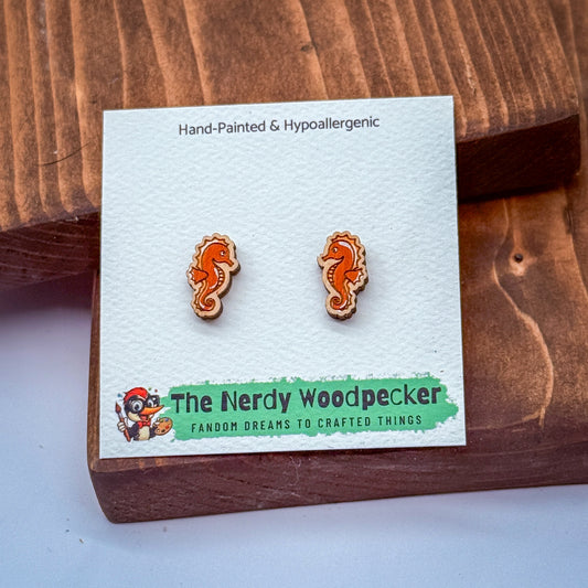 a pair of hand-painted and hypoallergenic earrings with a wooden design, displayed on a wooden surface.