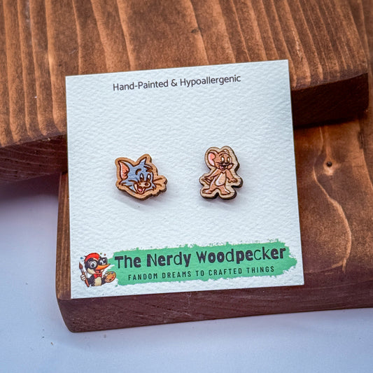 two wooden earrings with cartoon-like designs, placed on a wooden surface.