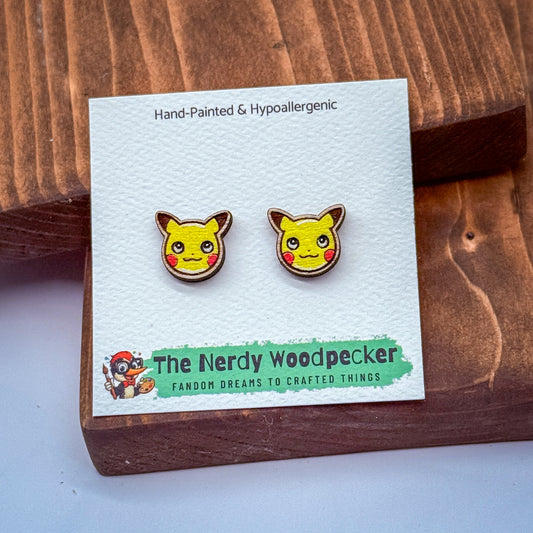 a pair of hand-painted Pokemon-themed earrings displayed on a wooden surface.