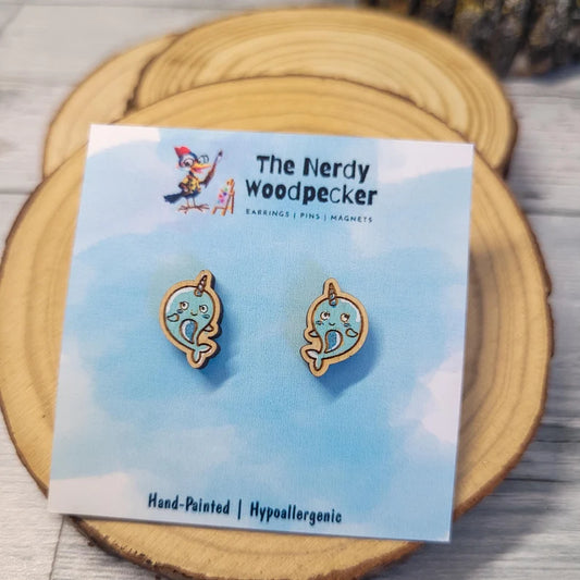 a pair of wooden earrings with a cute, cartoonish design, placed on a wooden coaster or plate.