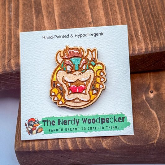 A hand-painted wooden pin featuring a cartoon character resembling Mario from the Mario series, with the text "The Nerdy Woodpecker" and "Fandom Dreams to Crafted Things" printed on it.