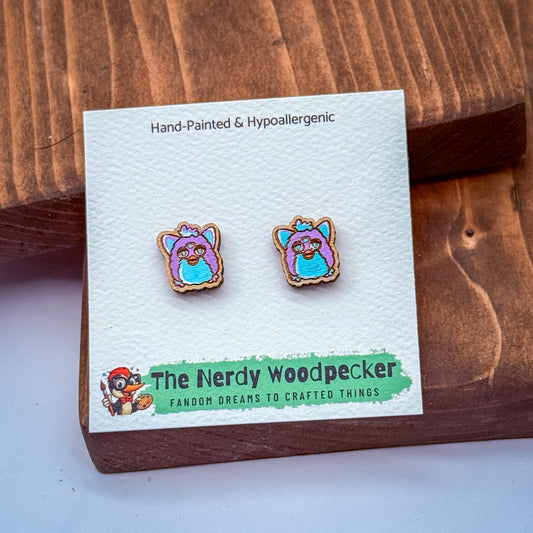 a pair of earrings in the shape of a cartoon character, placed on a white card with text and a logo.