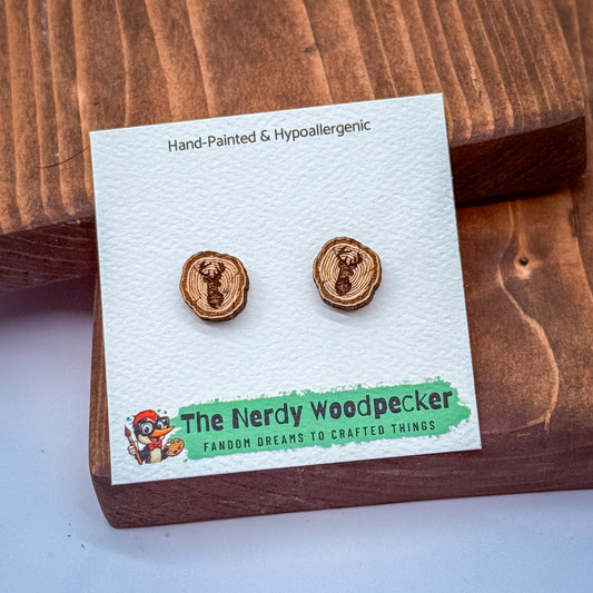 a pair of hand-painted wooden earrings from The Nerdy Woodpecker, displayed on a wooden surface.