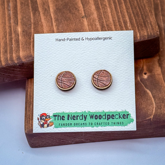 a pair of hand-painted and hypoallergenic earrings from The Nerdy Woodpecker, a fan of crafting and creating things. The earrings are displayed on a wooden surface, and the packaging features a cartoon character and text that describes the earrings as "Famous for their unique design and craftsmanship".